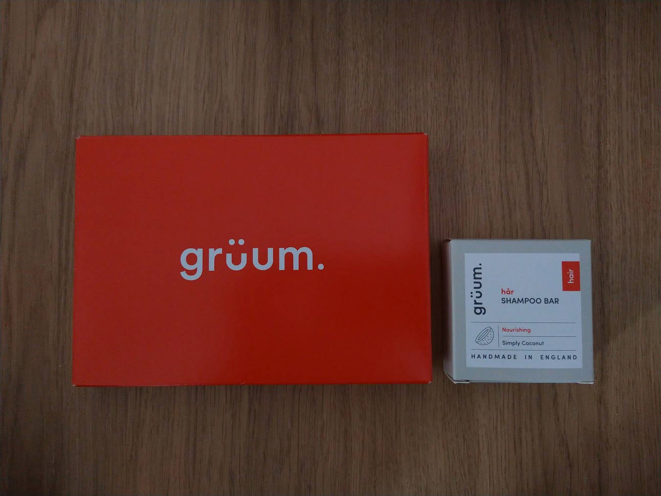 Grüum packaging: a red cardboard box beside the smaller square box that contains the shampoo bar.