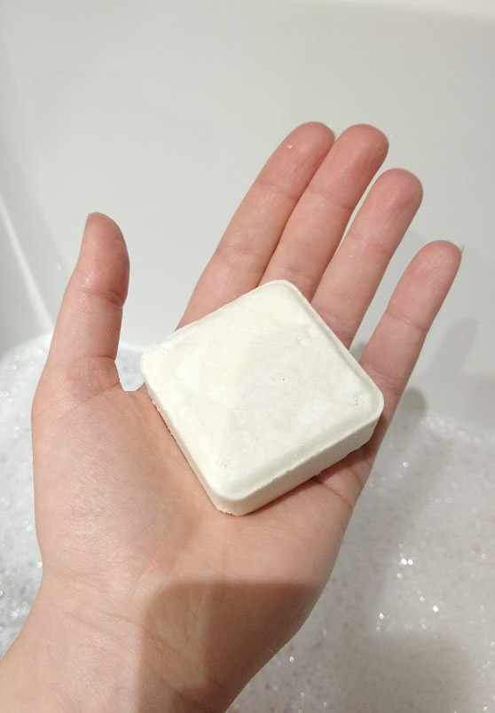 The Zero Waste Path square white shampoo bar in my hand.