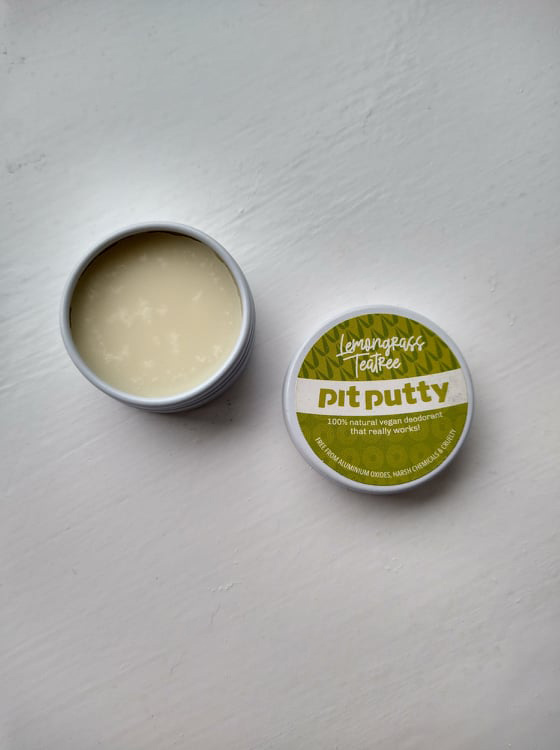 The small Lemongrass TeaTree Pit Putty tin open with the lid beside it.