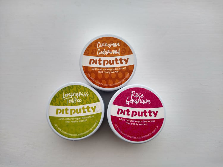 Three small tins of Pit Putty: orange for Cinnamon Cedarwood, green for Lemongrass TeaTree and pink for Rose Geranium.