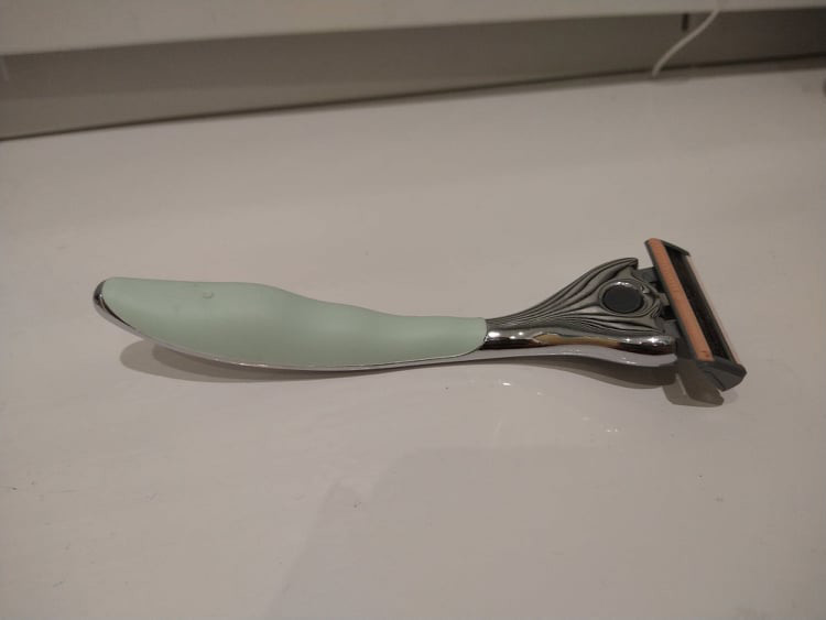 The underside of the FFS razor, showcasing the olive grip and pink strip on the blade.