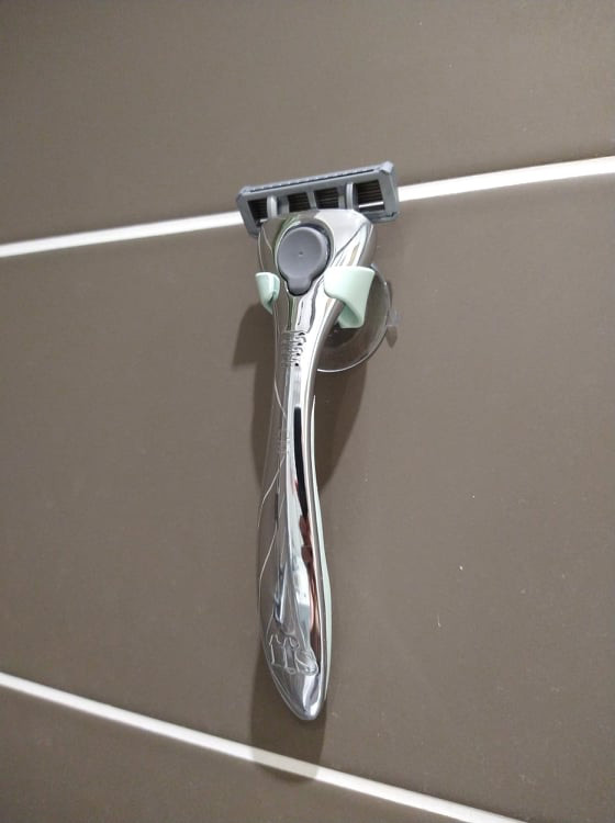 The FFS razor with the olive colour holder and grip, attached to bathroom tiles.