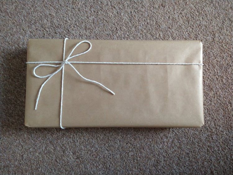 A rectangular present wrapped in brown paper with a string bow.