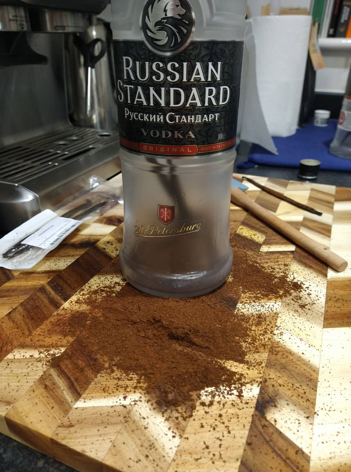 A bottle of Russian Standard vodka stood on a chopping board dusted with piles of ground coffee and vanilla pods.