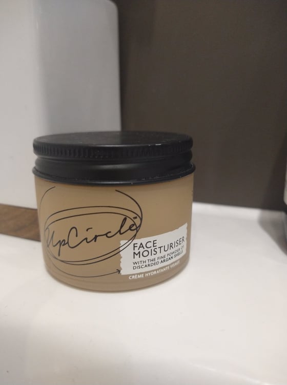 Upcircle's face moisturiser in a frosted peach glass tub with a black aluminium lid.