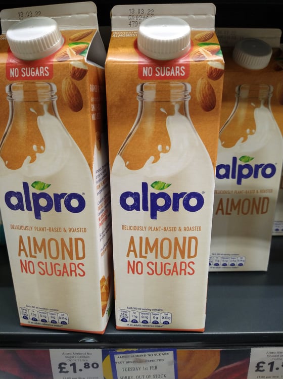 Cartons of Alpro Almond milk on the shelves at Tesco.