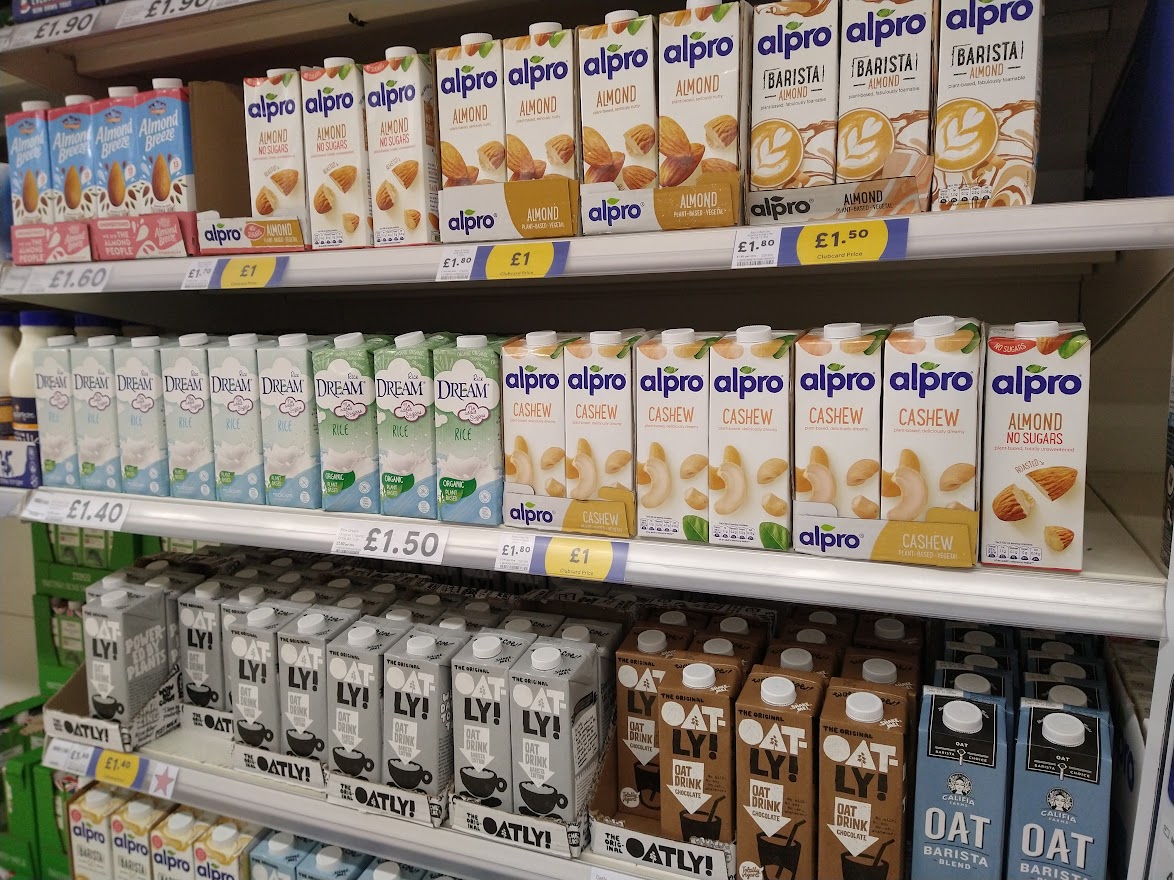 Three shelves of alternative milks in Tesco, including Oatly, Rice Dream, and Alpro.