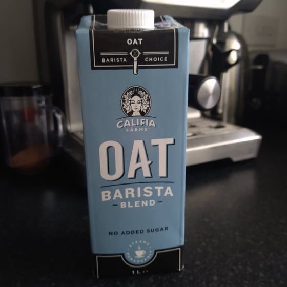 A blue carton of Califia oat barista milk, with our Sage coffee machine in the background.