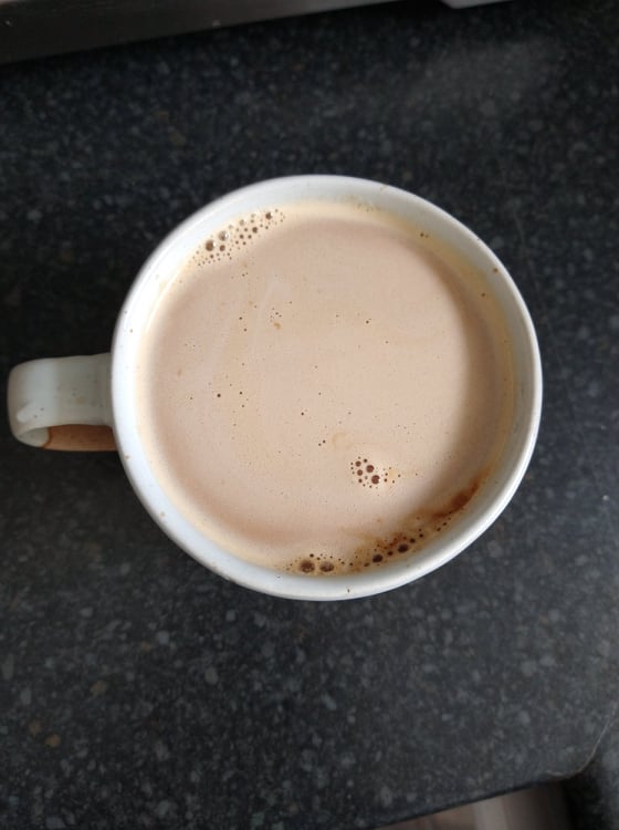 A cup of coffee with no foam with only a few bubbles where there should be foam.