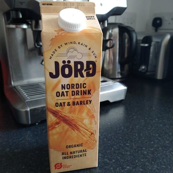 A beige carton of Jord oat and barley milk with our Sage coffee machine in the background.