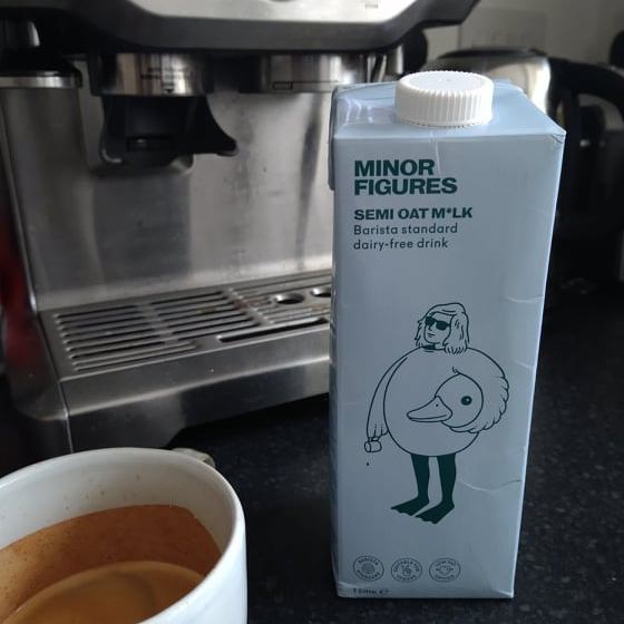 A blue carton of Minor Figures milk beside a mug of espresso and with our Sage coffee machine in the background.