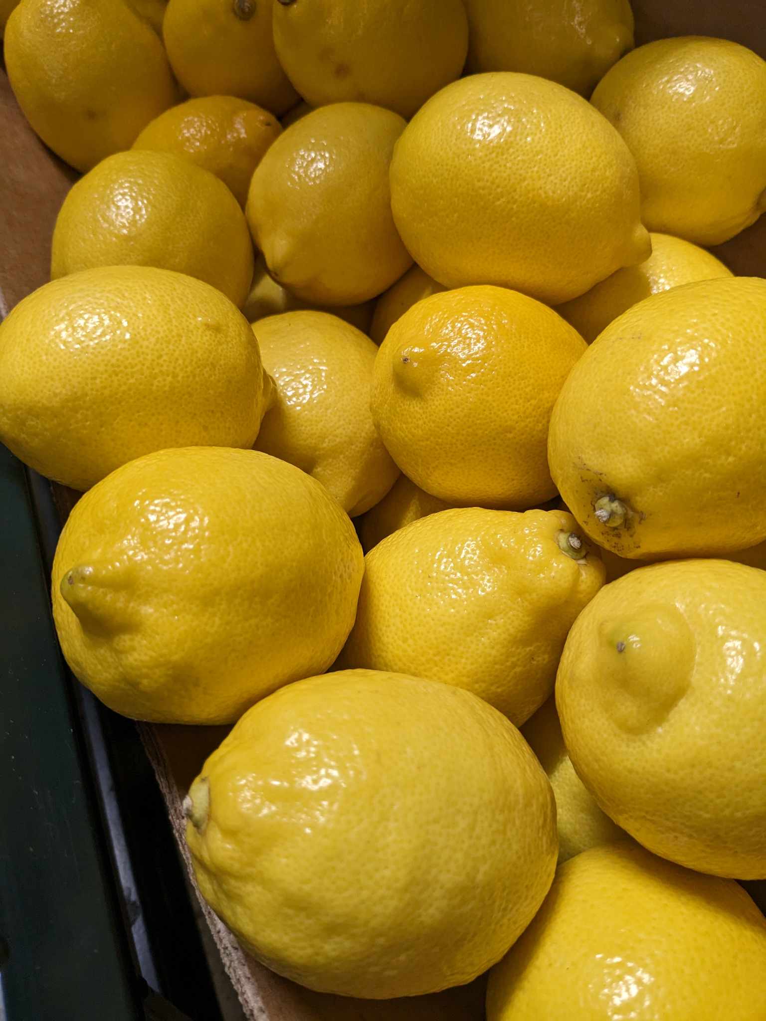 A pile of shiny lemons in a supermarket.