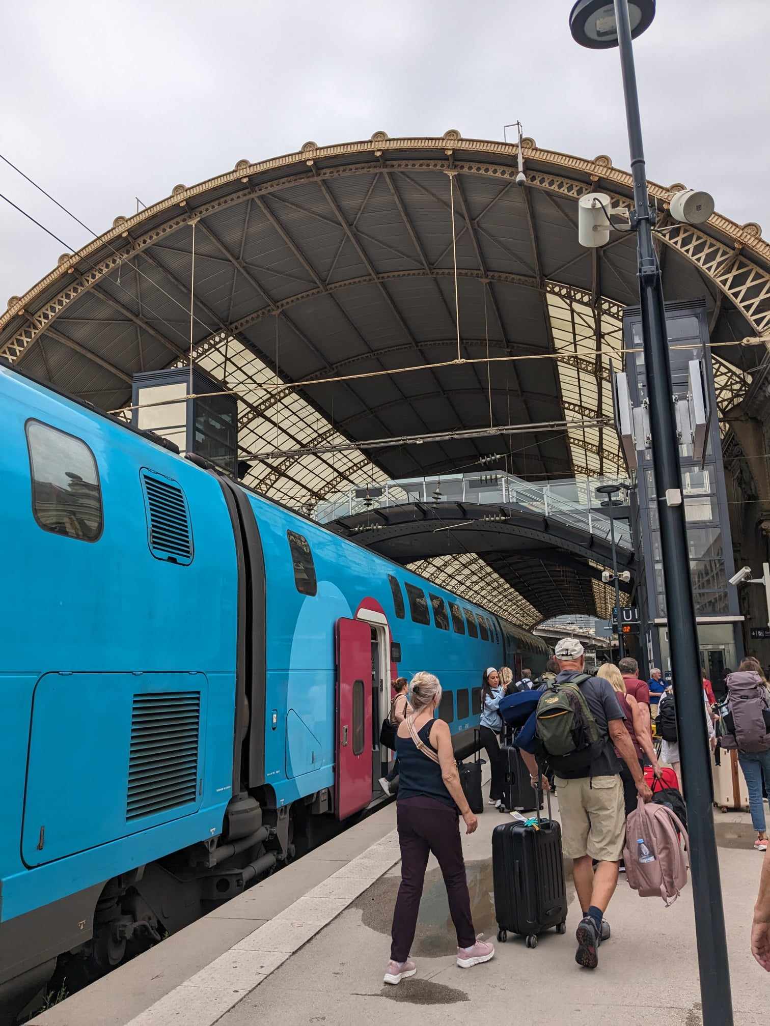 A blue double decker train pulled in to the curving roof of Nice Ville station.