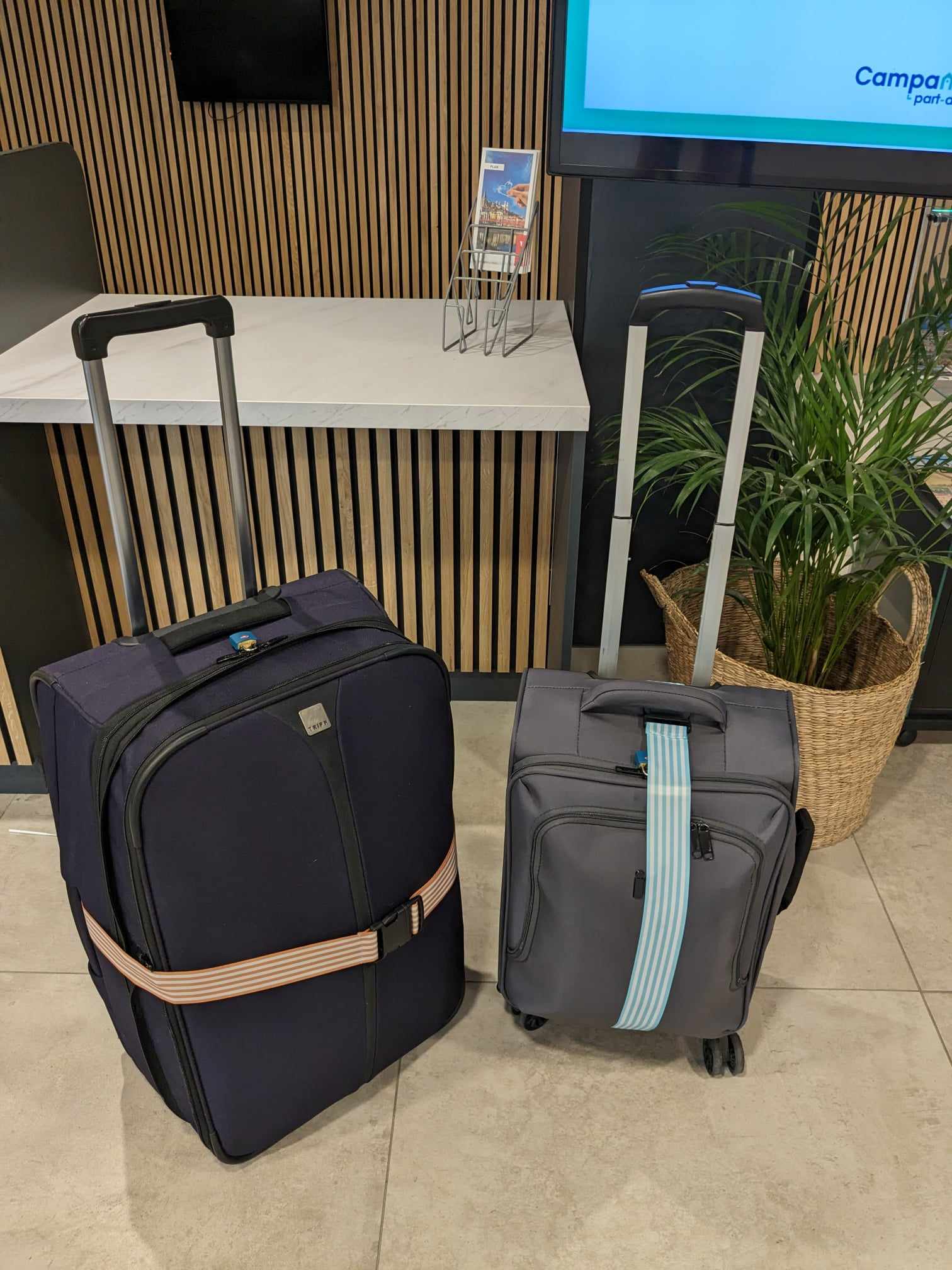 One large and one small suitcase at a hotel bag dropoff.