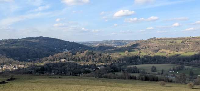 View over Cromford village, with rolling hills and a bright sunny sky.