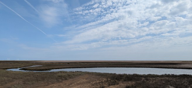 Coastline at Gibraltar Point, with sand dunes and a large stream joining the sea.