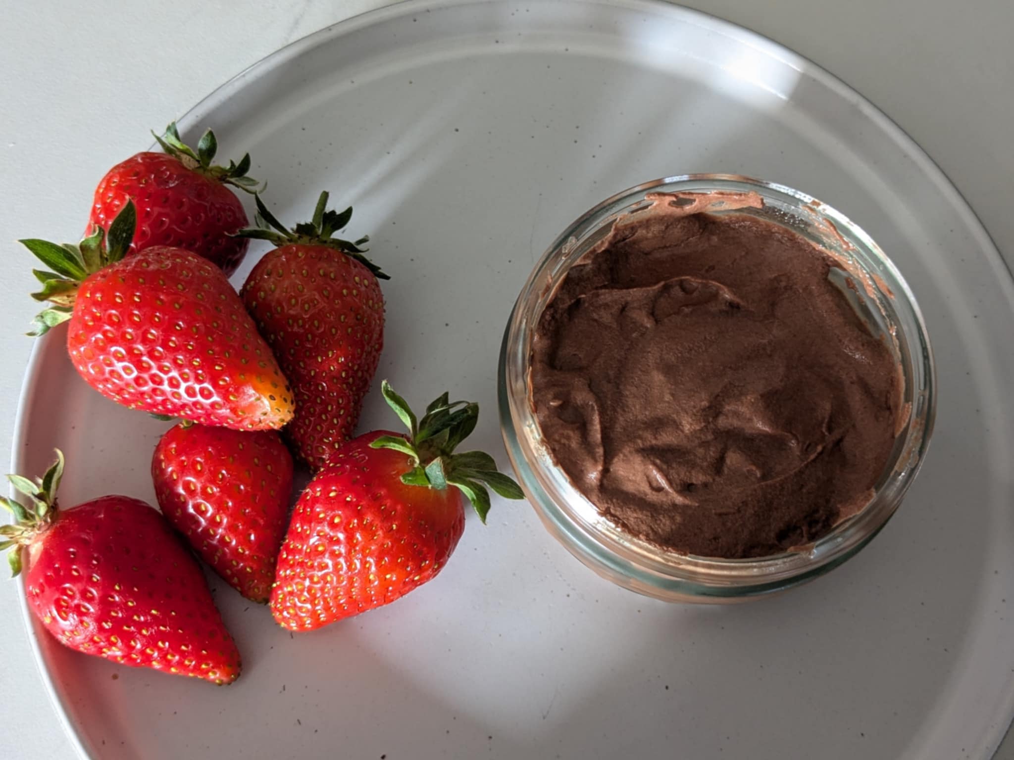 A homemade chocolate mousse pot with homegrown strawberries alongside.