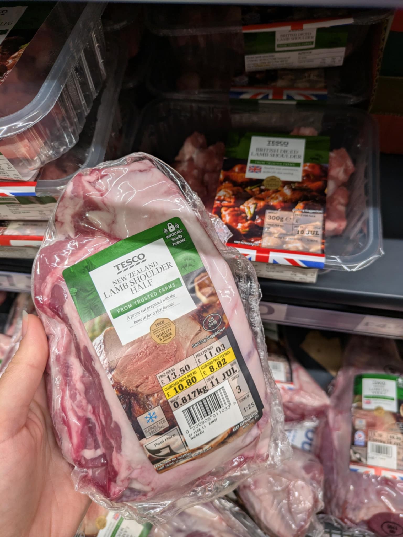 A vacuum-packed 800g half shoulder of lamb in Tesco, marked as £8.03 Clubcard price. On the shelf behind is a pack of diced lamb shoulder weighing 300g.