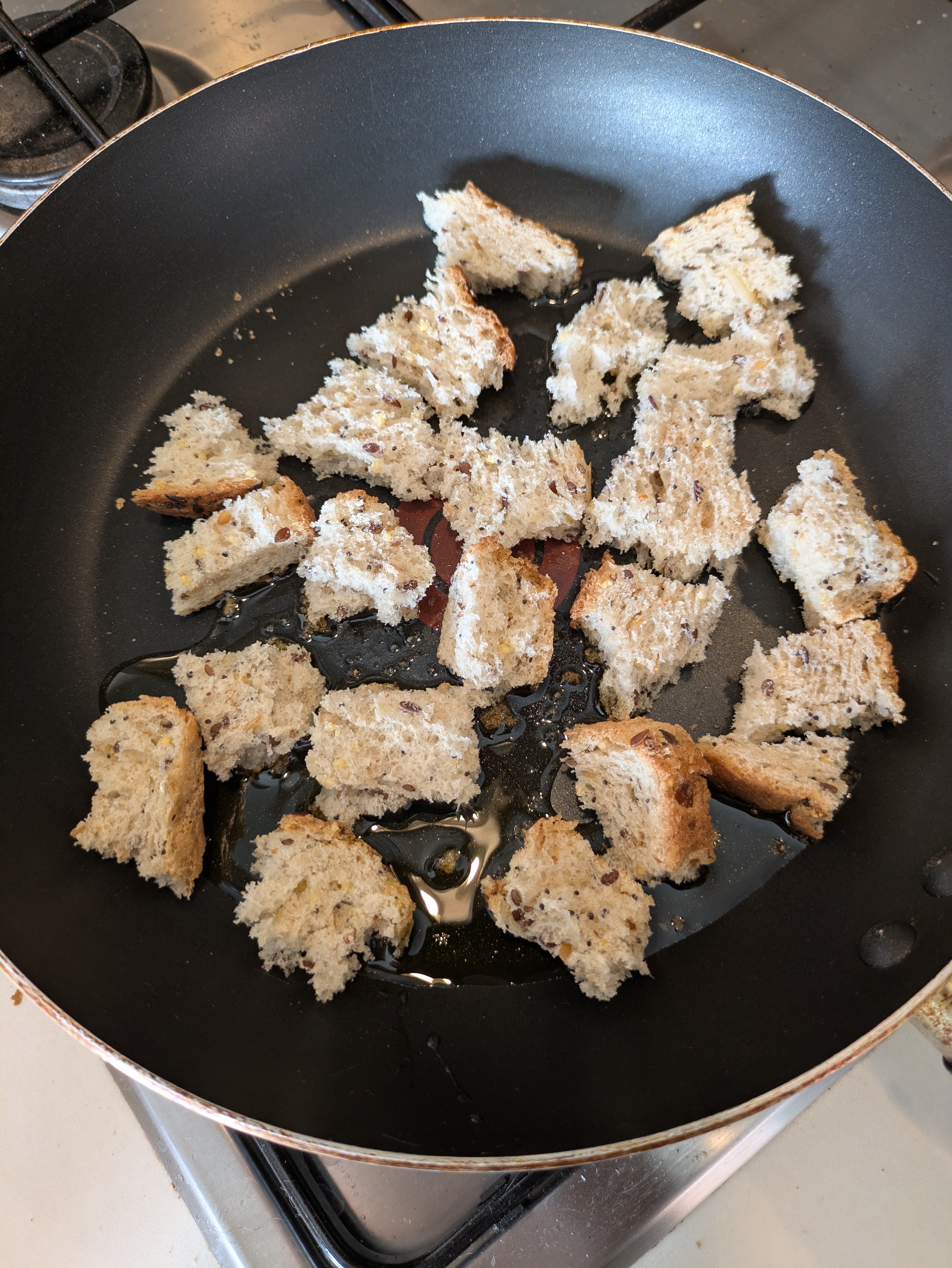 A pan full of cubes of bread in oil.
