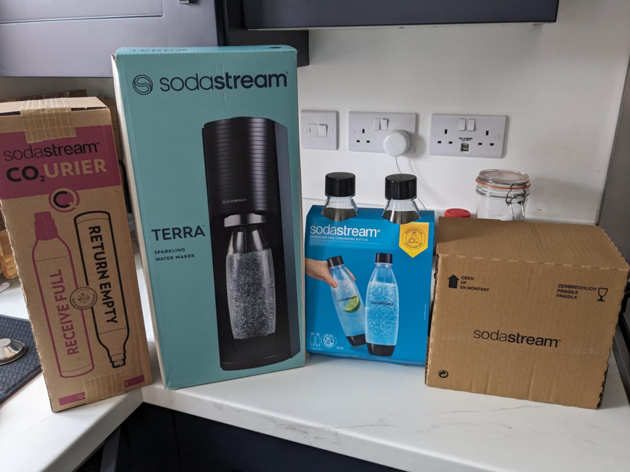 Our Sodastream bundle, from left to right: box of four gas canisters, the Terra water maker, a two-pack of extra bottles, and the box of syrups.