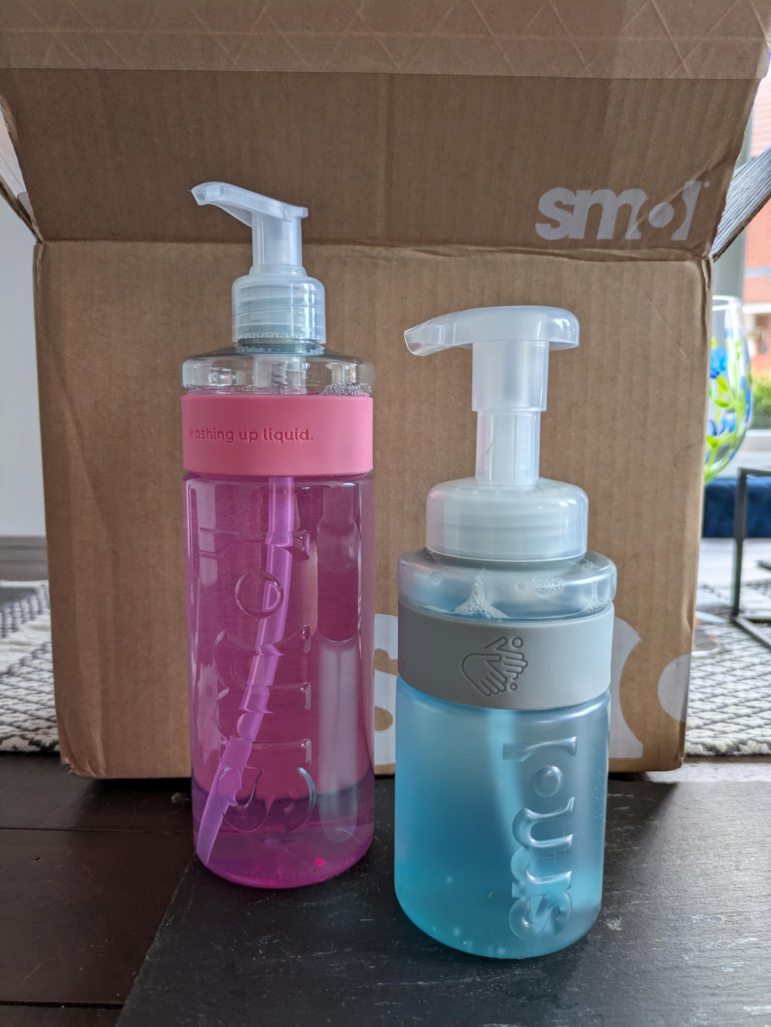 A bottle of Smol's pink washing up liquid and their blue handsoap.